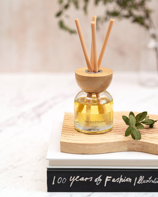 A luxury glass reed diffuser with Lime, Basil, and Mandarin fragrance oil, styled on a wooden shelf in a bright, modern Scottish home.
