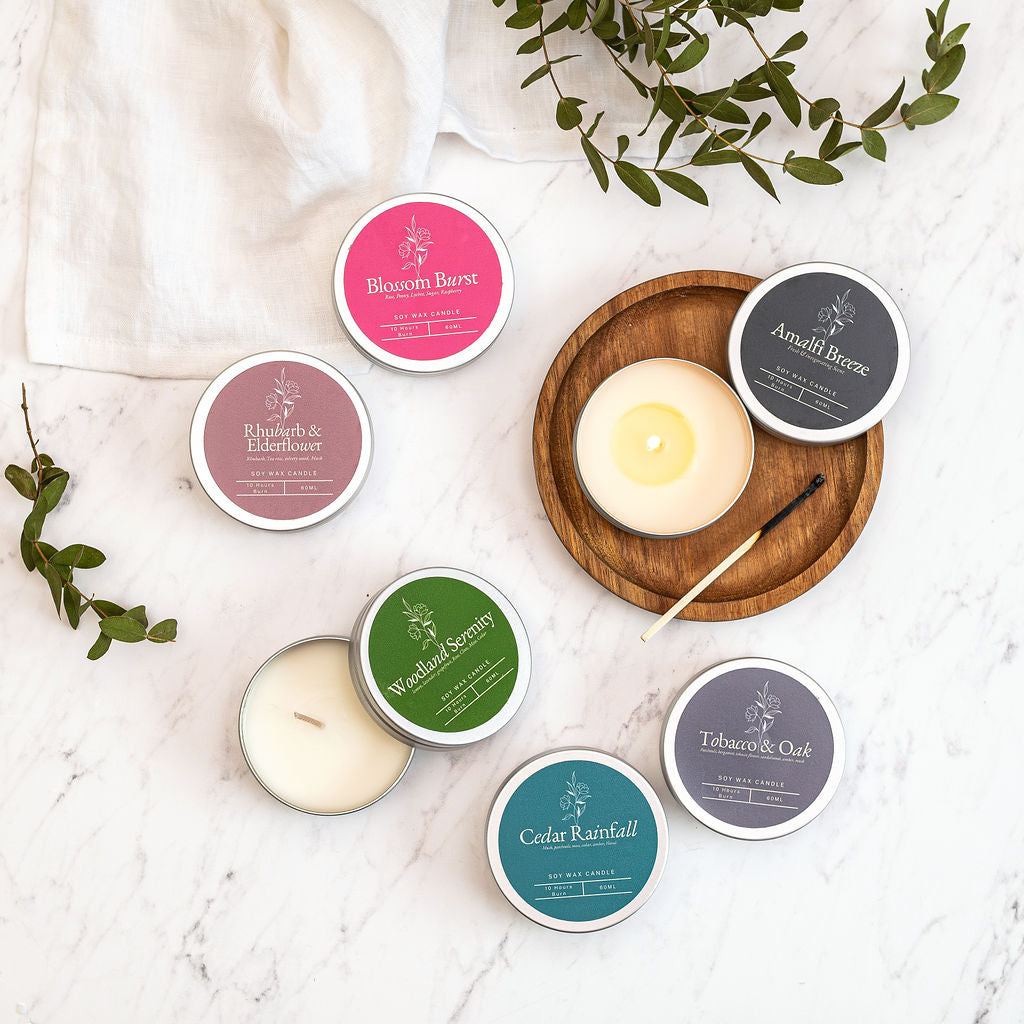 Collection of candles and candle tins with labels on a marble surface. Luxury soy candle discovery set by Myariella Candles creating a warm home fragrance atmosphere