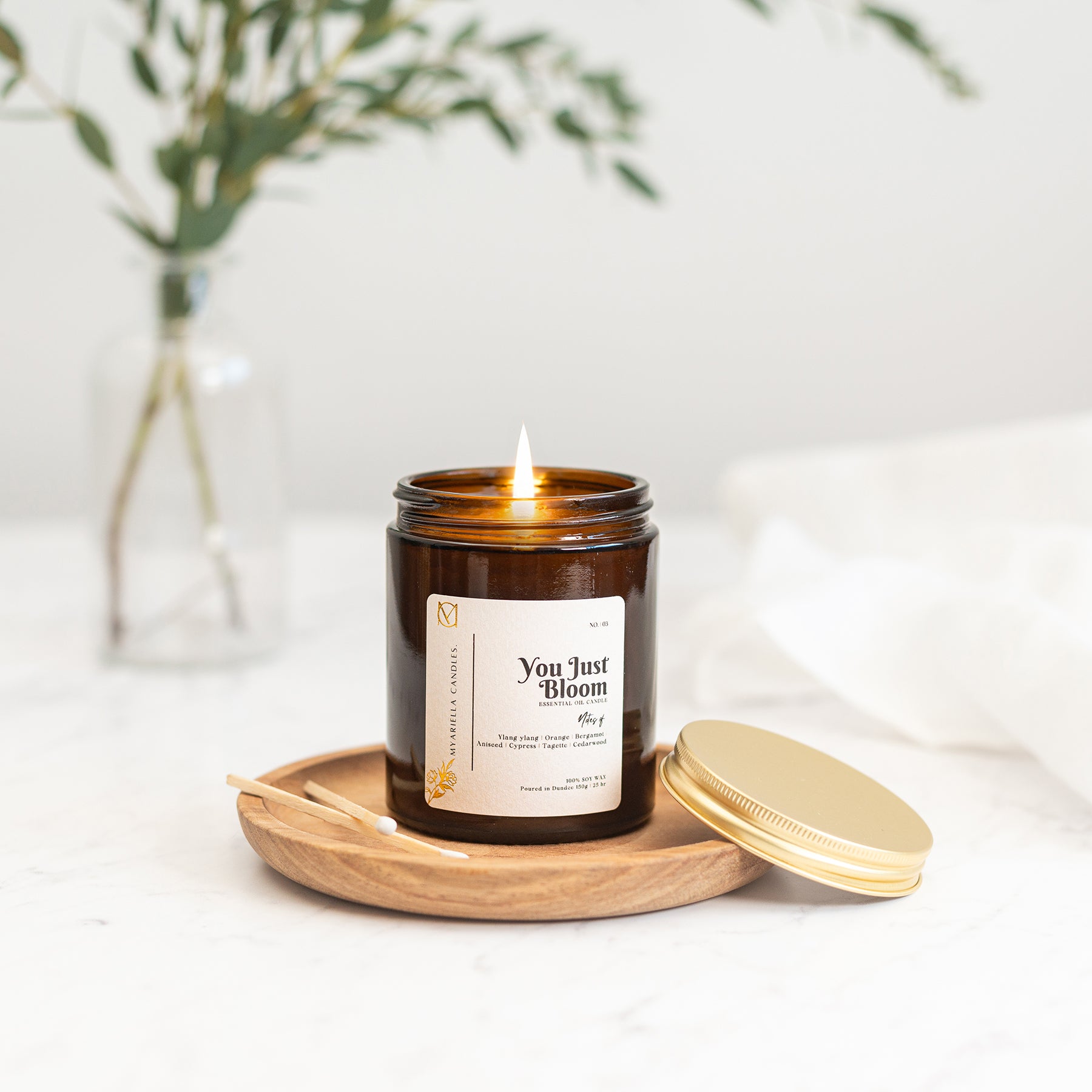 myariella candles natural gingerlily ylang-ylang essential oil candle creating a calming home fragrance atmosphere. candle in a amber jar glass 
