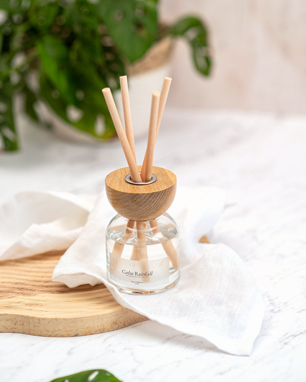 A non-toxic Cedar Rainfall reed diffuser placed on a modern bathroom vanity, providing a fresh, rain-soaked forest scent to a stylish UK home.